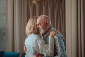 elderly couple standing in a room and hugging