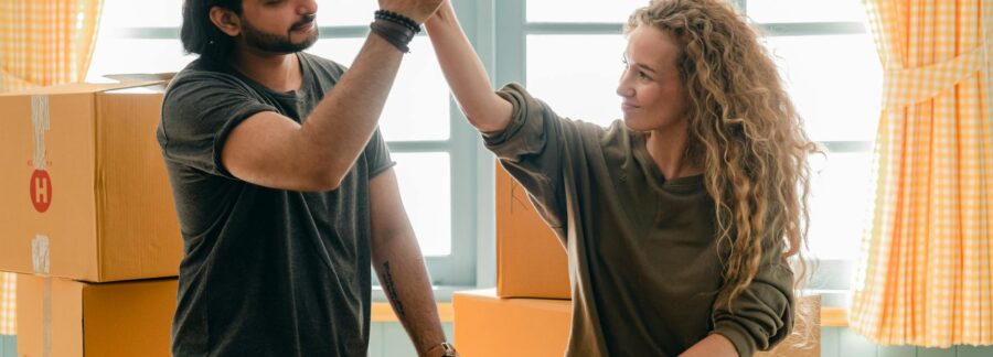 multiracial couple giving high give standing near pile of boxes