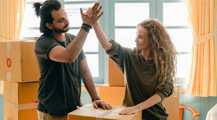 multiracial couple giving high give standing near pile of boxes