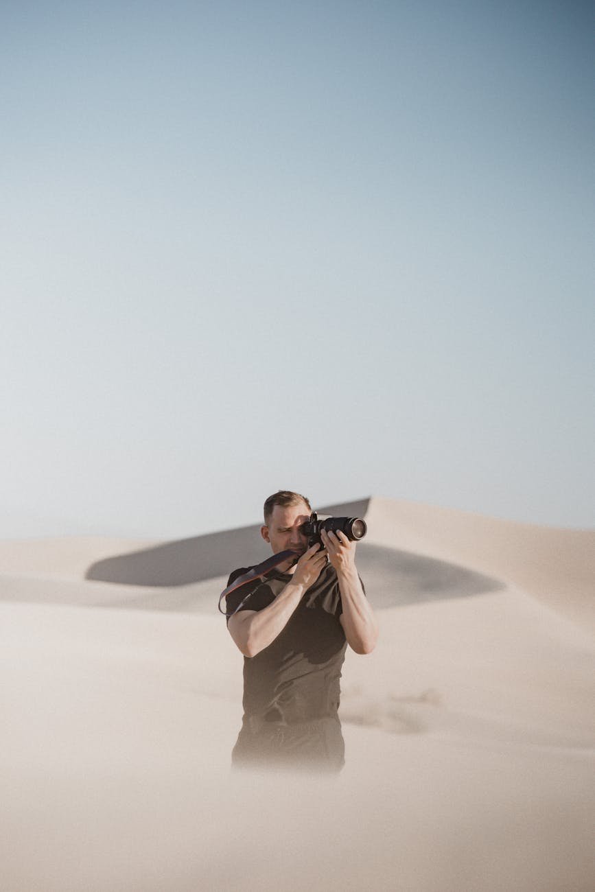 man taking picture with camera on desert
