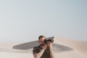 man taking picture with camera on desert