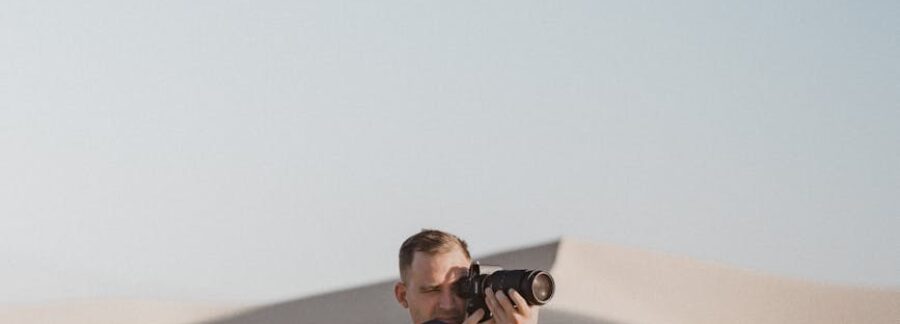 man taking picture with camera on desert