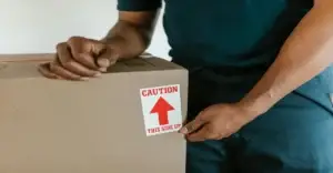Dedicated Moving short-notice relocation assistance; close-up of a moving box with caution labeling.